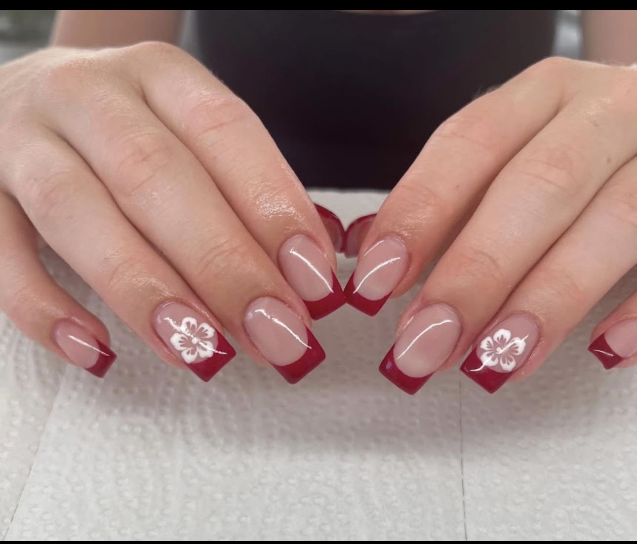 Rote French-Nägel mit weißer Blüte